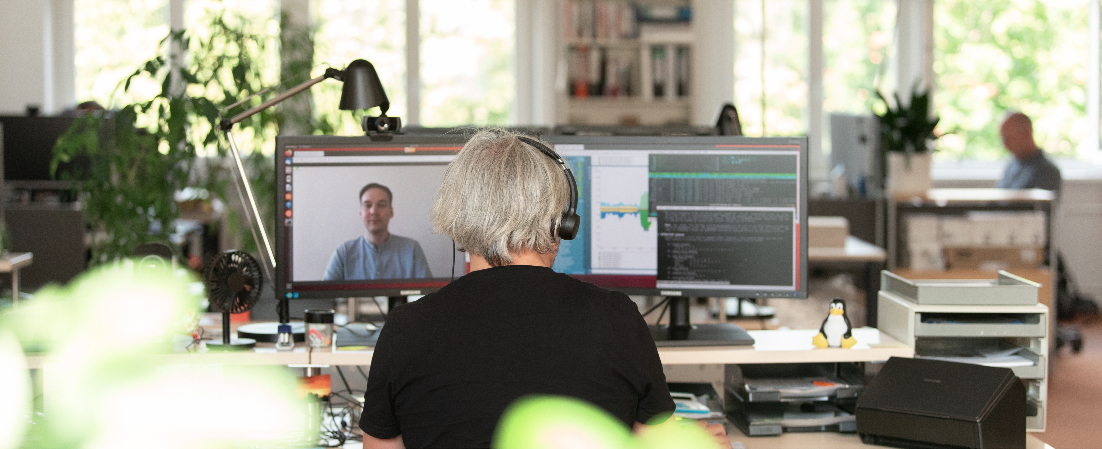Man with headphones seen from behind in a video conference
