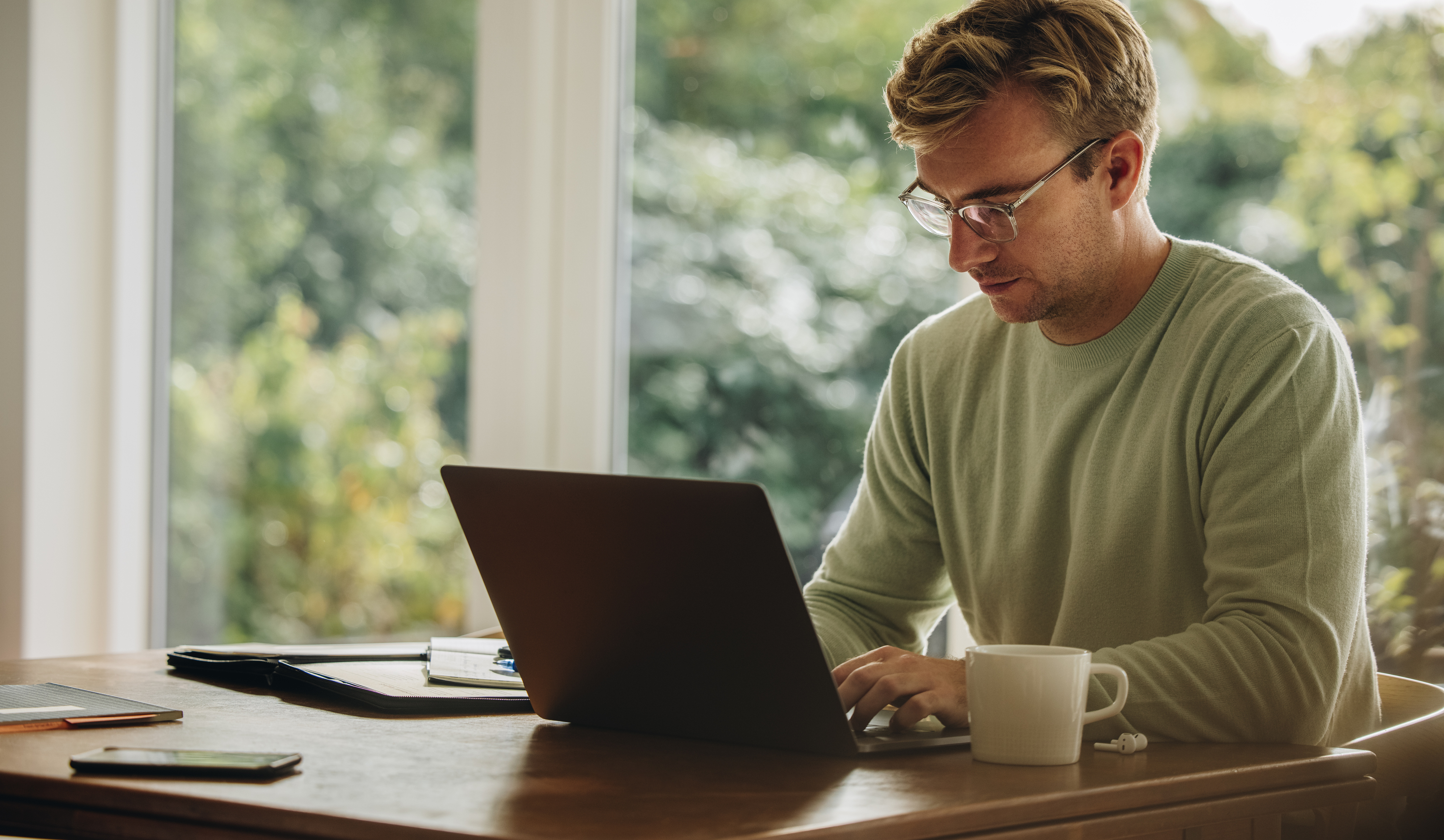 Junger Mann, der am Laptop arbeitet. Mann, der zu Hause am Tisch sitzt und einen Laptop benutzt.