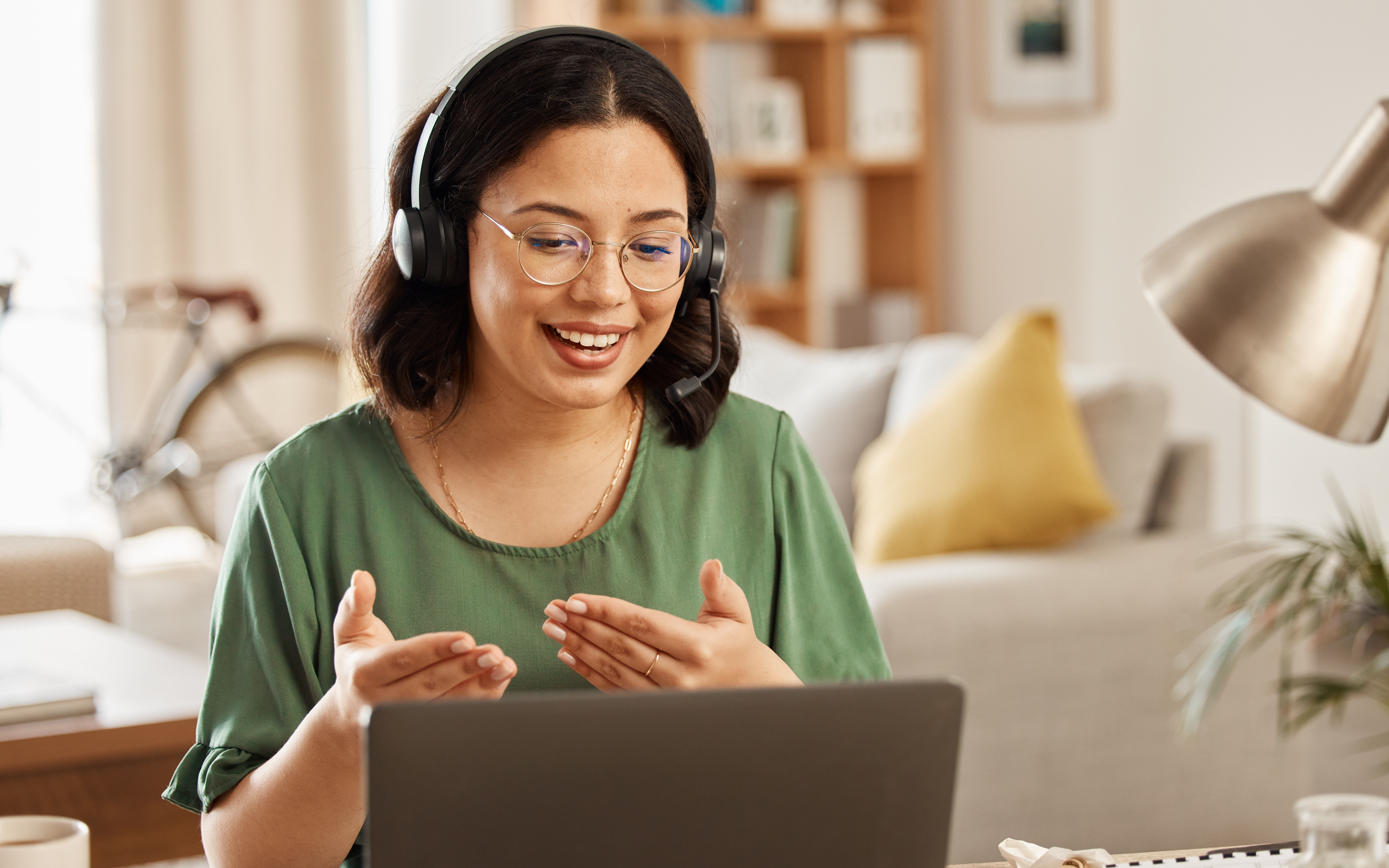 Frau mit Headset sitzt vor einem Laptop und nimmt an einem Videocall teil