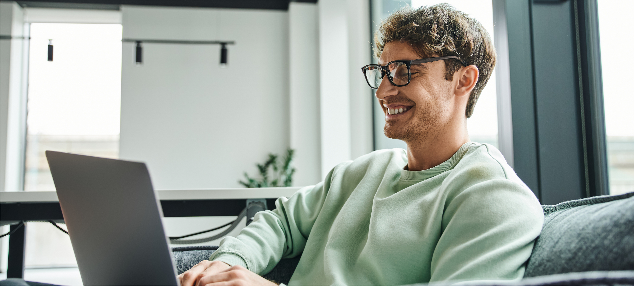 Mann sitzt am Laptop und freut sich